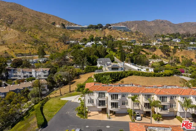 an aerial view of residential houses with outdoor space and trees