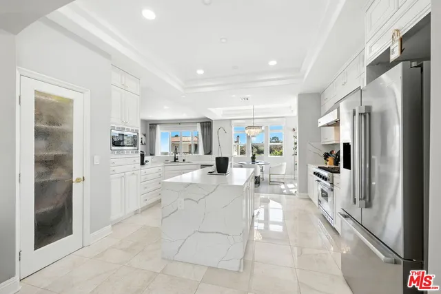 a large white kitchen with cabinets a sink and stainless steel appliances