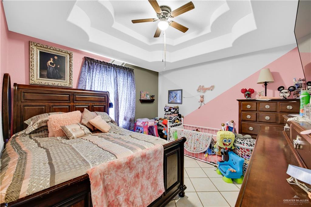 695 El Paisano Road Rio Grande City, TX 78582 - Photo 12 of 30 Bedroom featuring ceiling fan, a tray ceiling, and light tile patterned floors