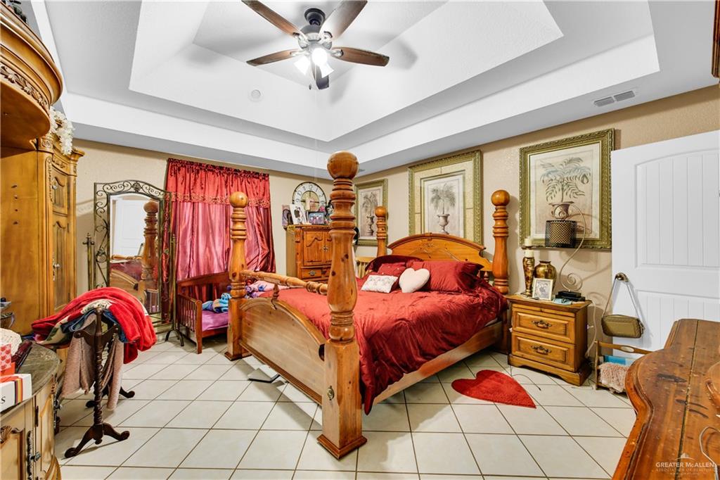 695 El Paisano Road Rio Grande City, TX 78582 - Photo 15 of 30 Bedroom with a tray ceiling, ceiling fan, and light tile patterned flooring