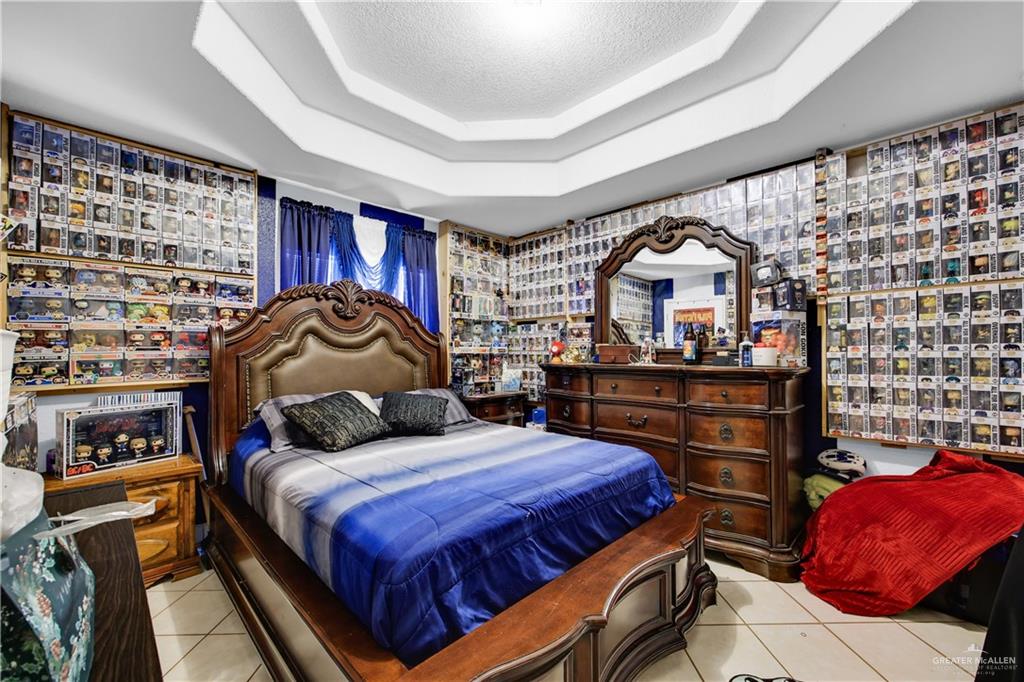 695 El Paisano Road Rio Grande City, TX 78582 - Photo 16 of 30 Bedroom with light tile patterned floors, a tray ceiling, and a textured ceiling