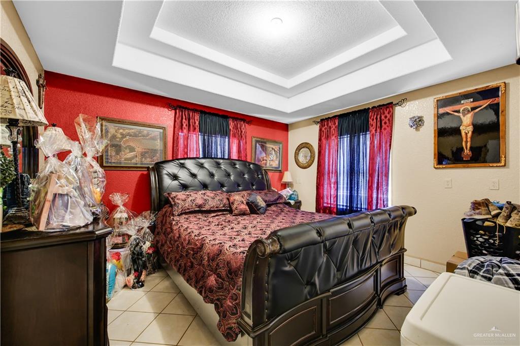 695 El Paisano Road Rio Grande City, TX 78582 - Photo 17 of 30 Bedroom featuring light tile patterned floors, a tray ceiling, and a textured ceiling