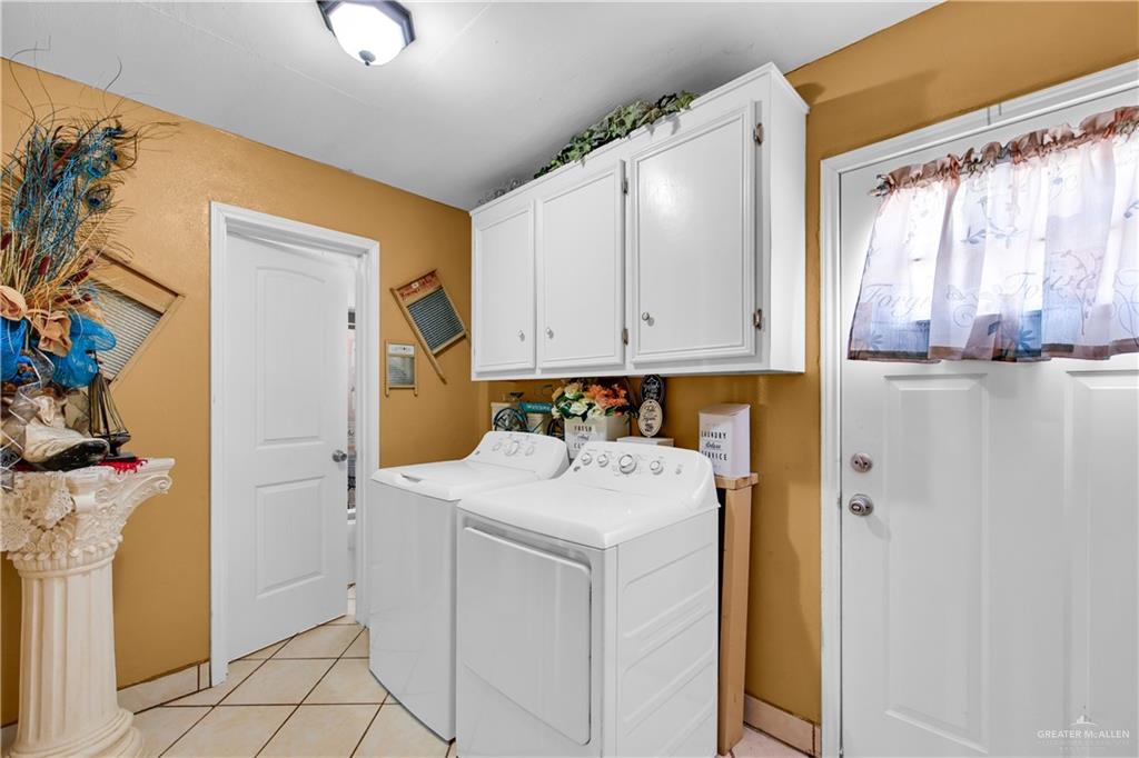 695 El Paisano Road Rio Grande City, TX 78582 - Photo 19 of 30 Laundry area featuring washer and clothes dryer, light tile patterned floors, and cabinet space