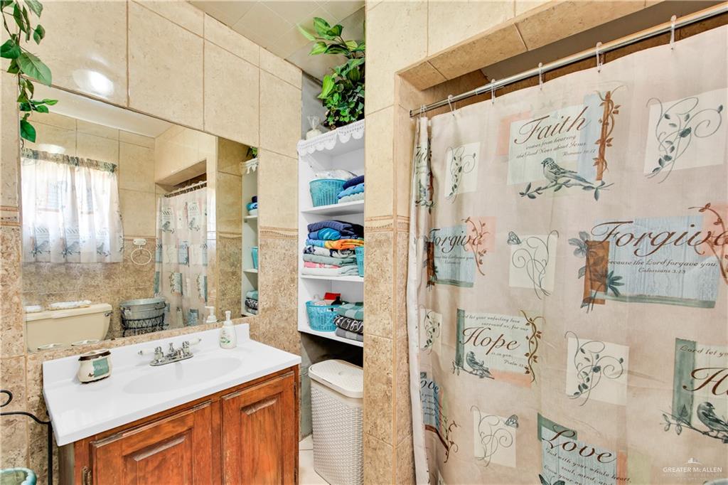 695 El Paisano Road Rio Grande City, TX 78582 - Photo 20 of 30 Bathroom featuring vanity, a shower with shower curtain, and tile walls