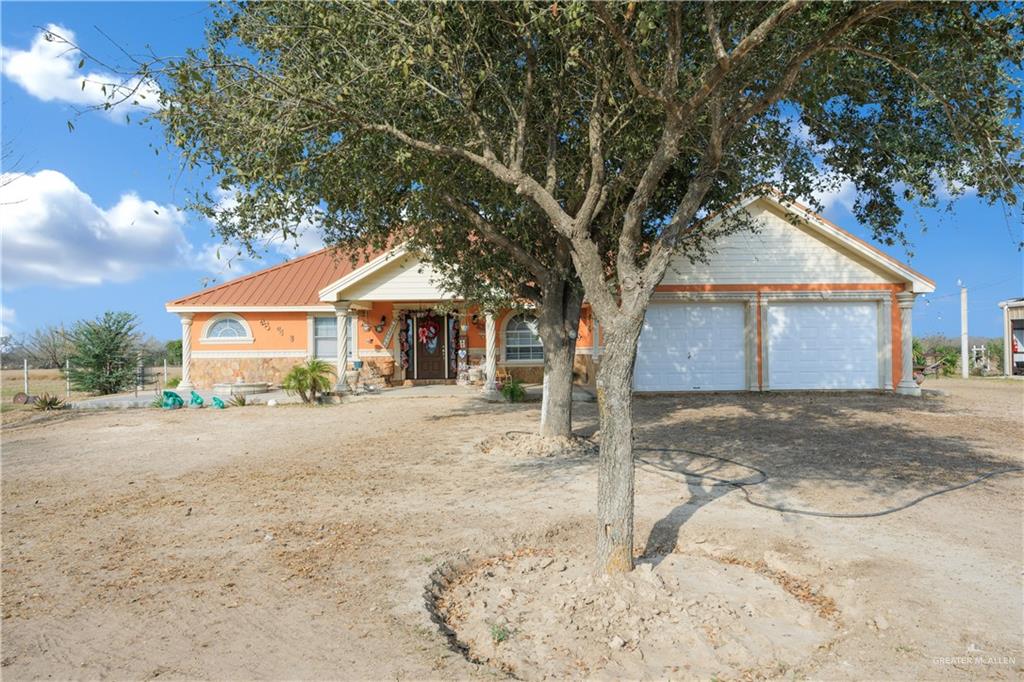 695 El Paisano Road Rio Grande City, TX 78582 - Photo 2 of 30 Ranch-style house with driveway, a metal roof, and an attached garage