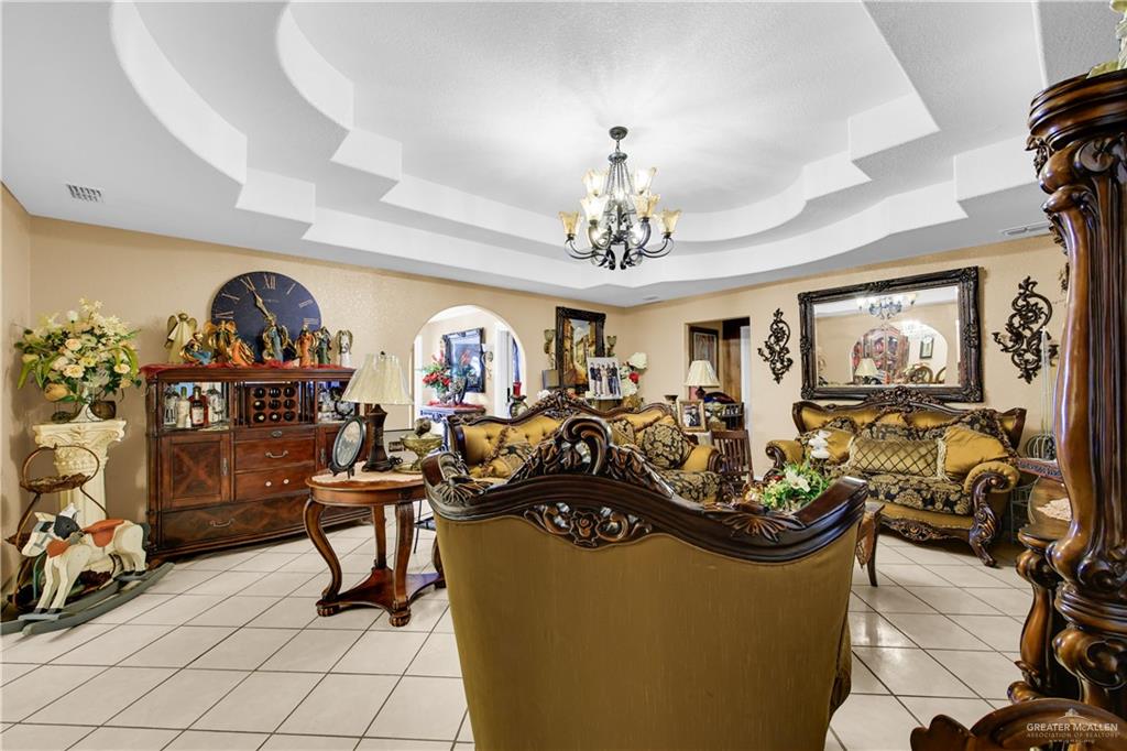 695 El Paisano Road Rio Grande City, TX 78582 - Photo 22 of 30 Living area featuring light tile patterned floors, a chandelier, and a raised ceiling