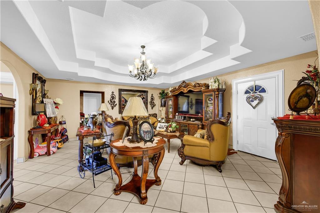 695 El Paisano Road Rio Grande City, TX 78582 - Photo 10 of 30 Living room with a chandelier, light tile patterned floors, and a raised ceiling