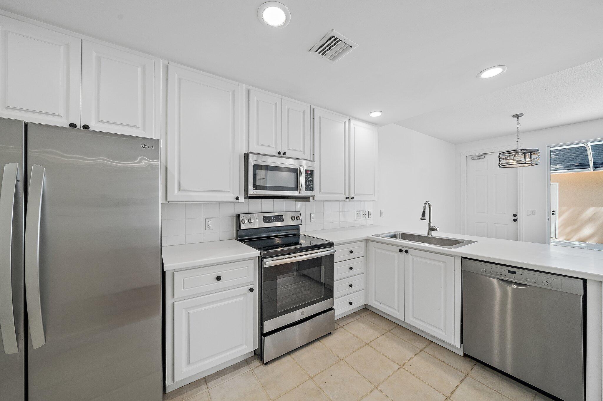 304 Legare Court Jupiter, FL 33458 - Photo 14 of 38 a kitchen with white cabinets sink and stainless steel appliances