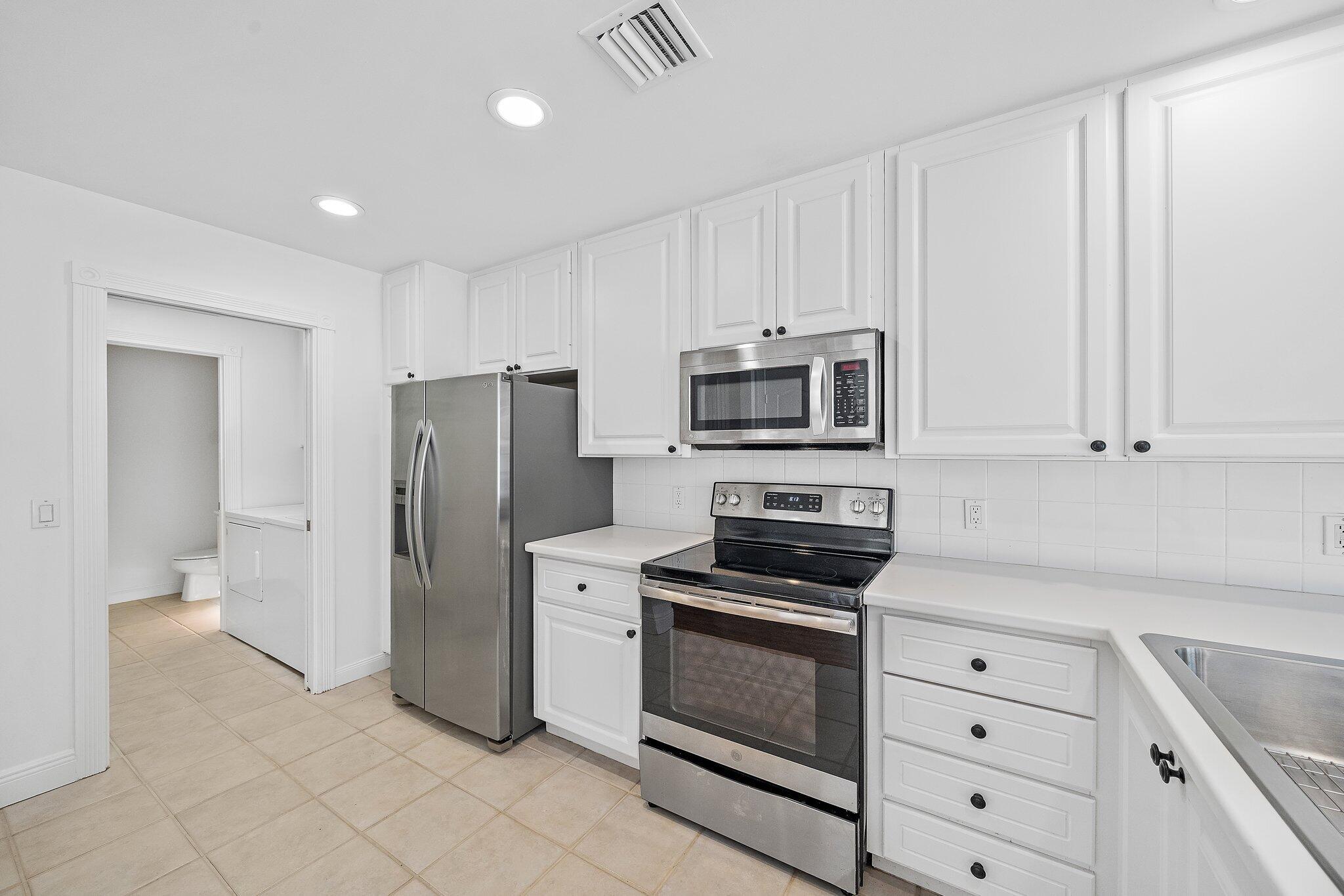 304 Legare Court Jupiter, FL 33458 - Photo 15 of 38 a kitchen with white cabinets and stainless steel appliances