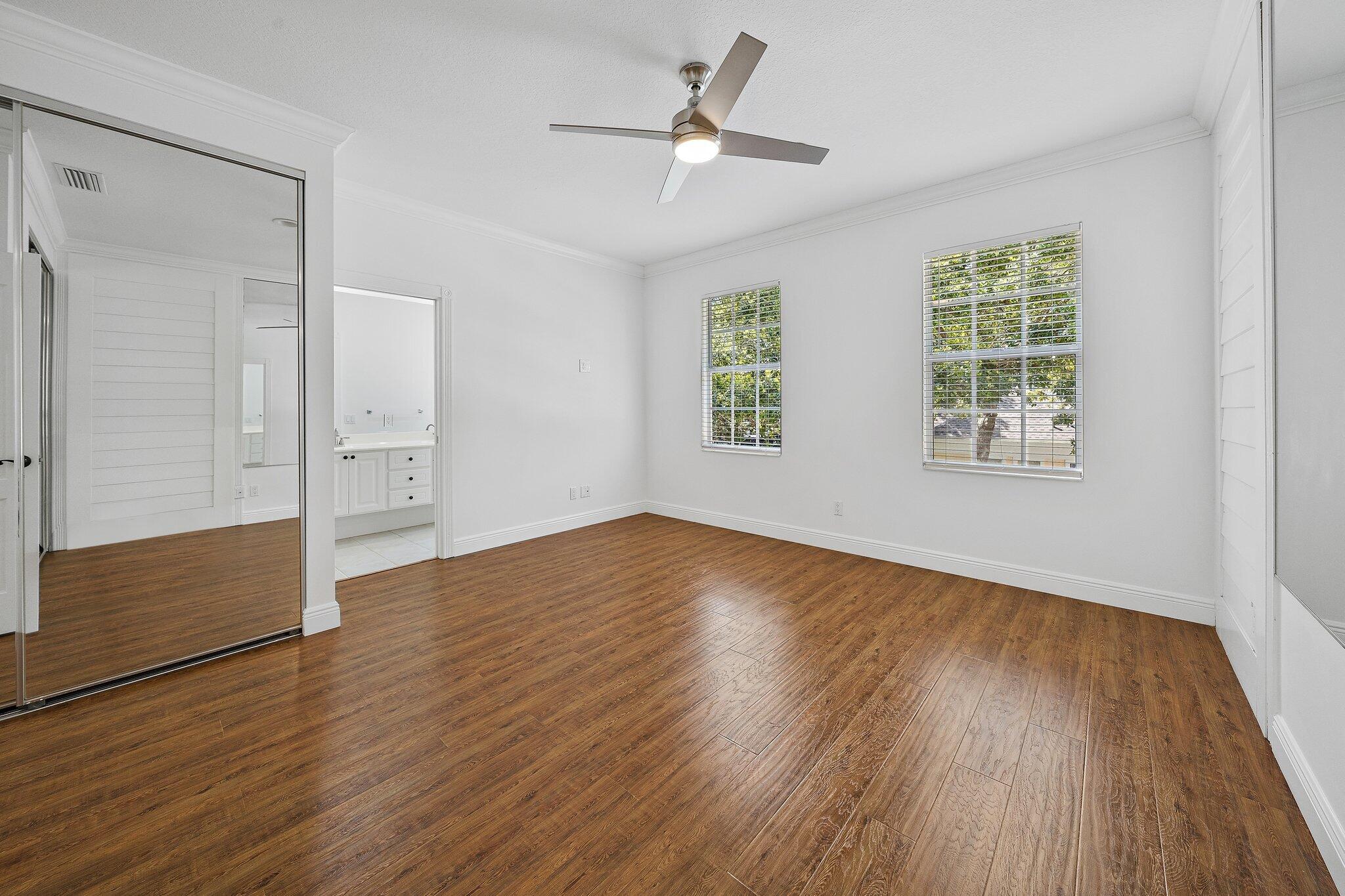 304 Legare Court Jupiter, FL 33458 - Photo 20 of 38 an empty room with wooden floor chandelier fan and windows