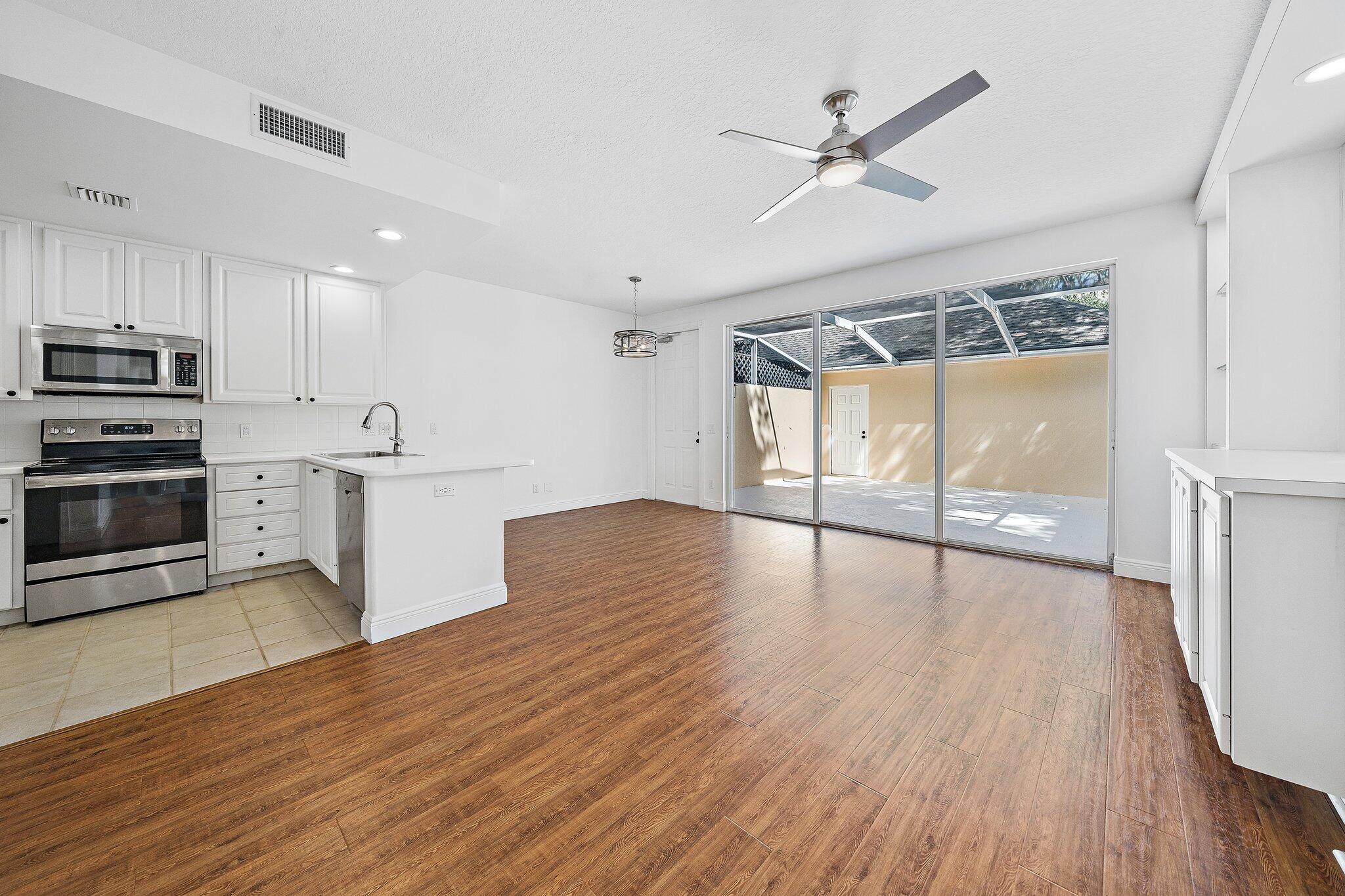 304 Legare Court Jupiter, FL 33458 - Photo 7 of 38 a view of a kitchen with wooden floor and a ceiling fan