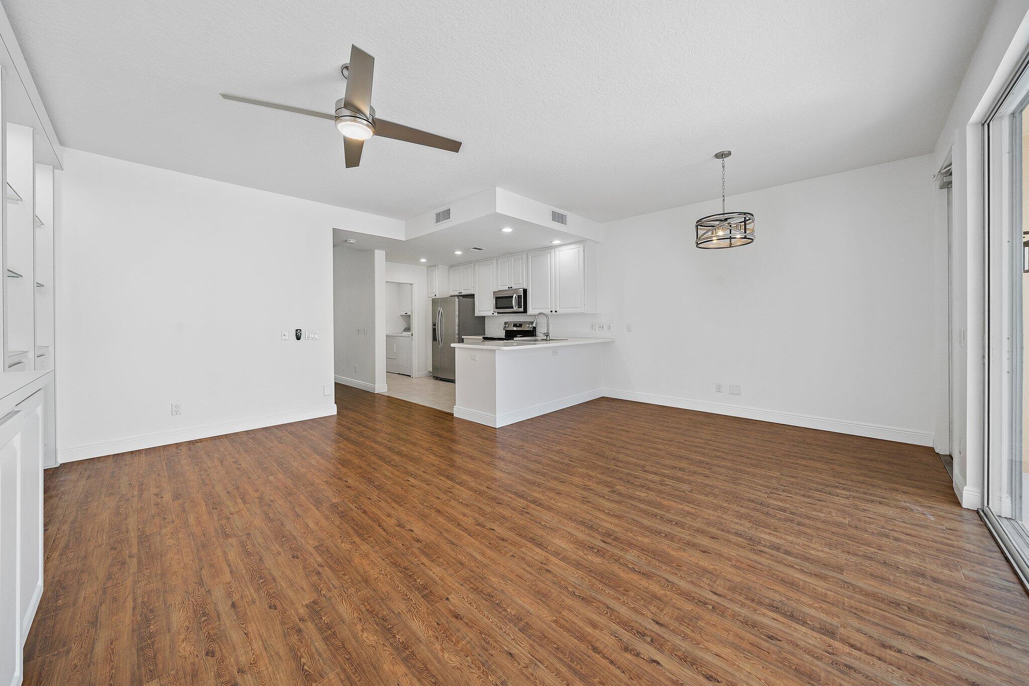 304 Legare Court Jupiter, FL 33458 - Photo 9 of 38 a view of a kitchen with a wooden floor and a ceiling fan
