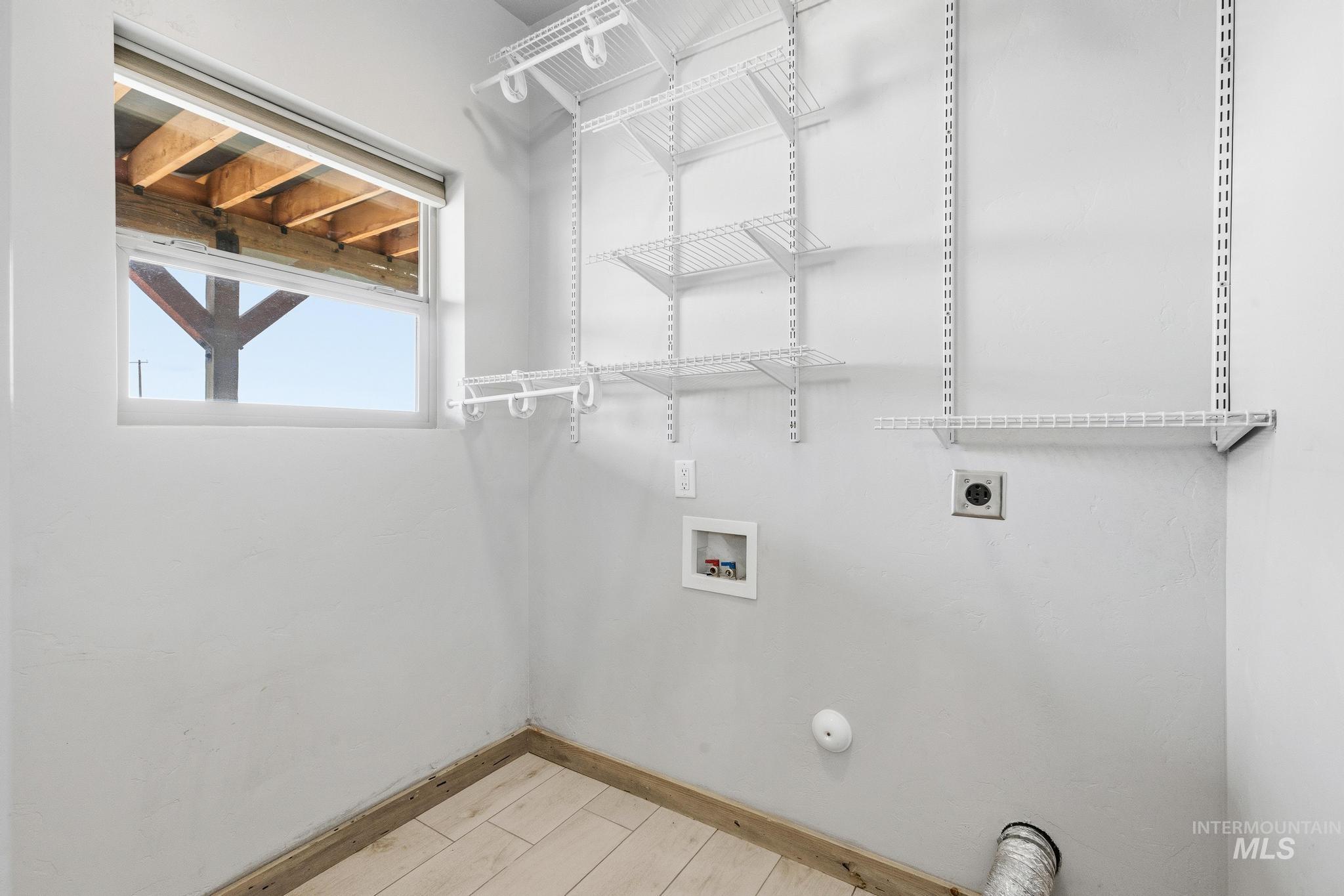 870 Desert Wind Road Boise, ID 83716 - Photo 22 of 50 Dedicated utility space featuring a window, built-in wire shelving, and wood-finish flooring