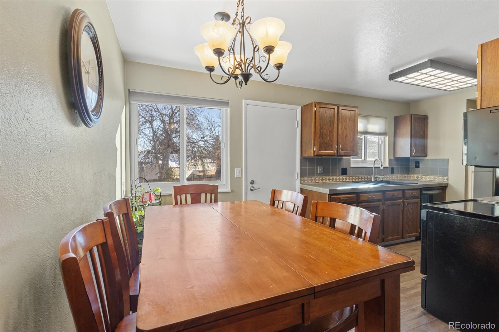 4262 South Quintero Way Aurora, CO 80013 - Photo 5 of 36 a dining room with stainless steel appliances granite countertop wooden floor a chandelier a large window and a kitchen view
