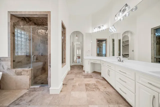 a spacious en suite bathroom with a double vanity sink a mirror and a shower