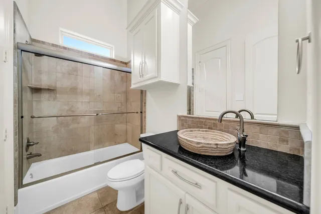 a bathroom with a granite countertop sink a toilet and shower