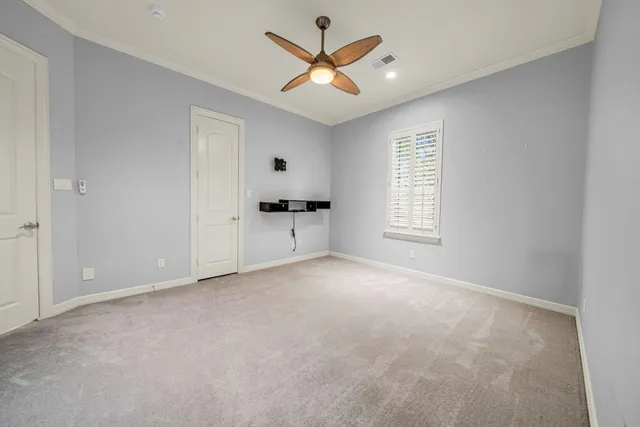 an empty room with chandelier fan and windows
