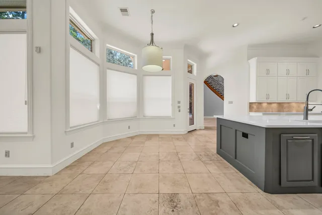 a large kitchen with granite countertop a stove a sink and a chandelier