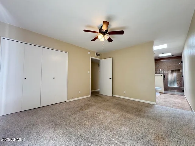 an empty room with ceiling fan and window