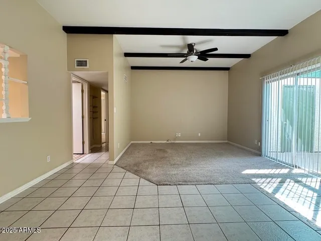 an empty room with a ceiling fan and window