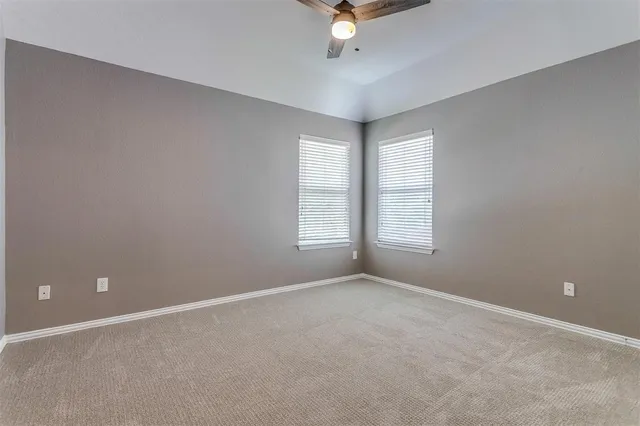 an empty room with a ceiling fan and windows