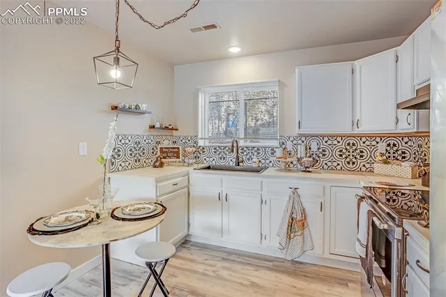a kitchen with stainless steel appliances a white table chairs and a refrigerator