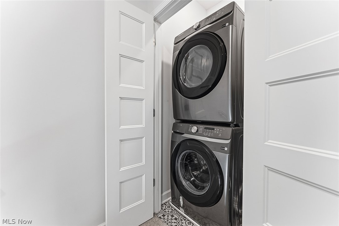2308 Fulton Road Cleveland, OH 44113 - Photo 22 of 30 Dedicated laundry area featuring a stacked washer and dryer, white paneled doors, and patterned floor tiling