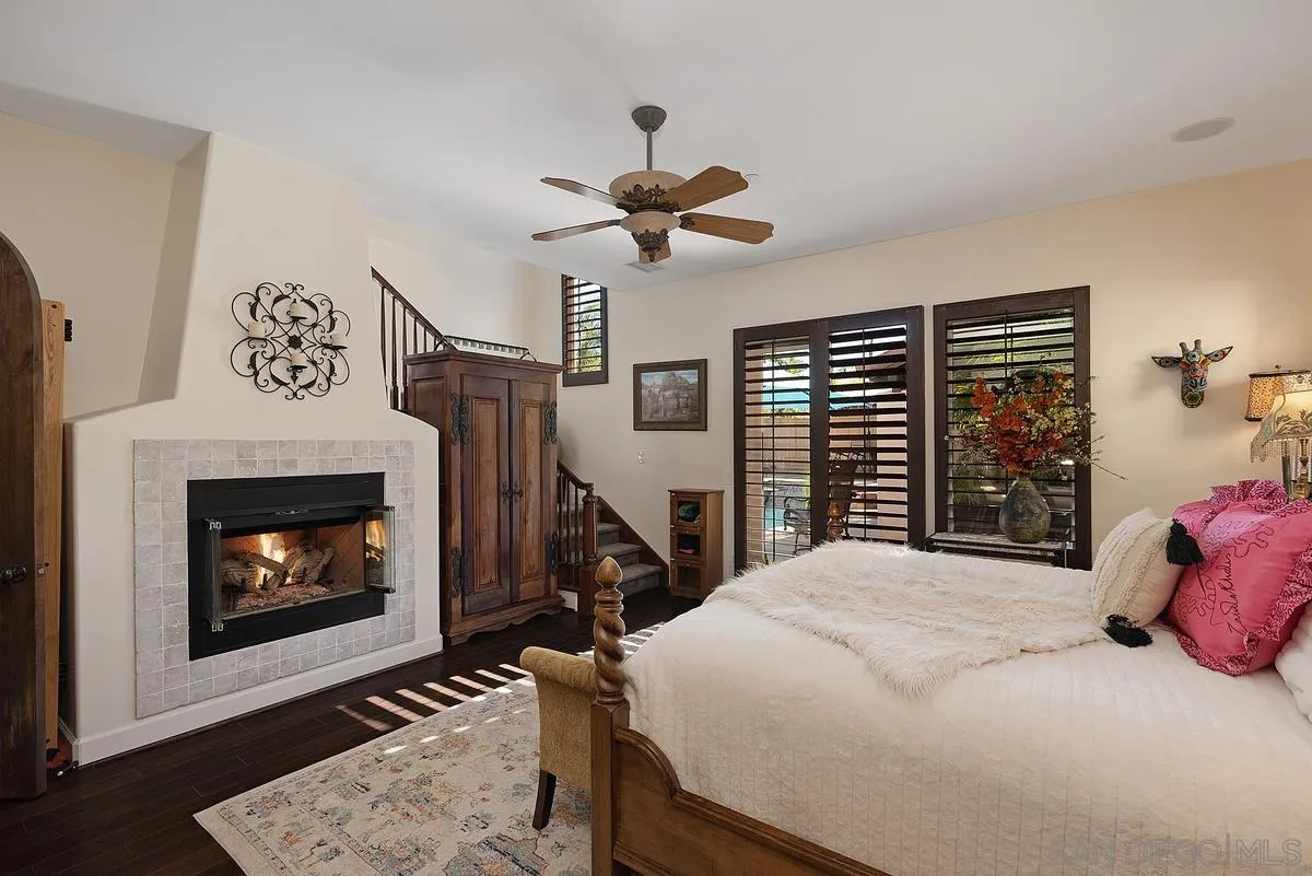 14779 Rio Rancho San Diego, CA 92127 - Photo 21 of 35 a bedroom with a bed a fireplace and a chandelier