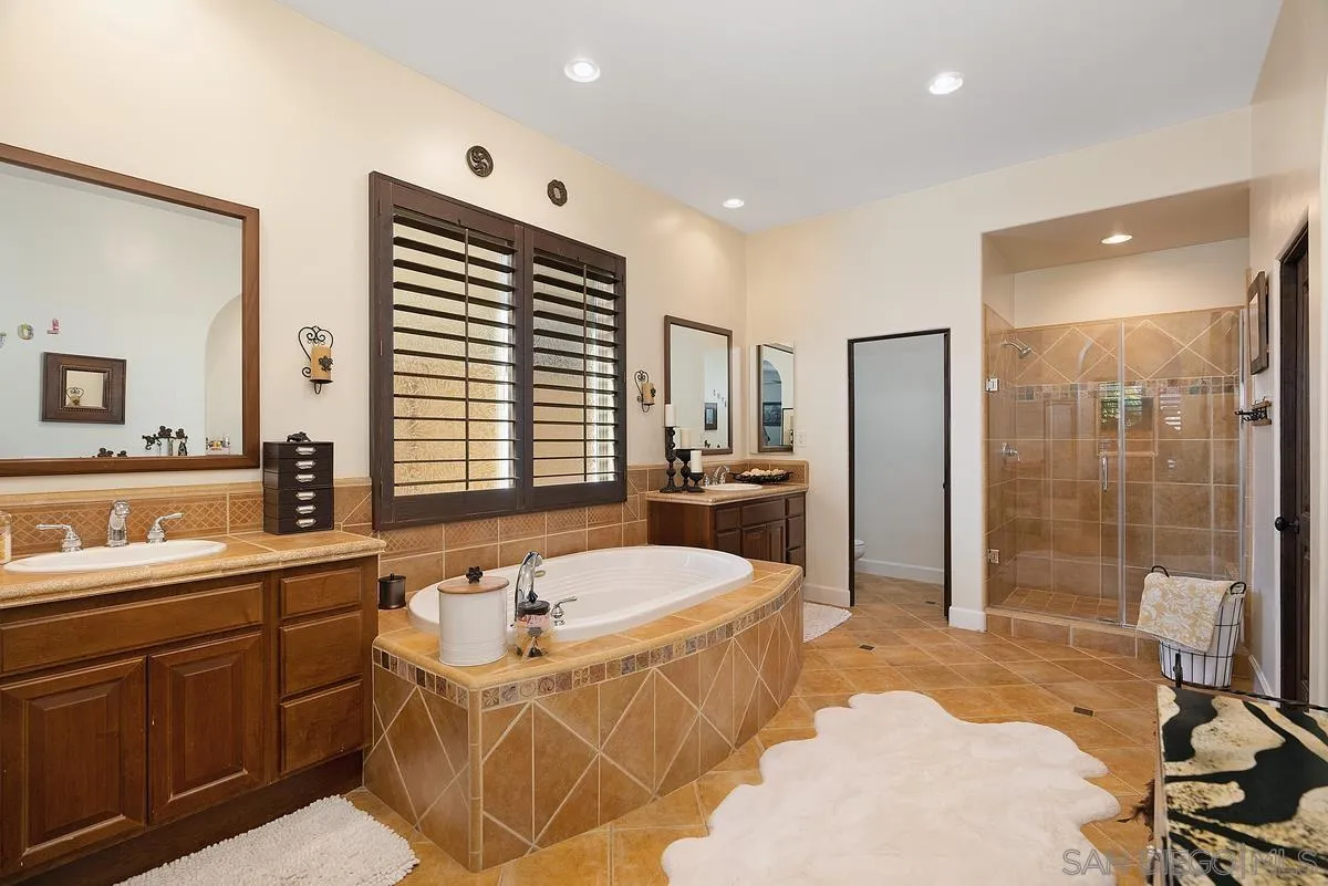 14779 Rio Rancho San Diego, CA 92127 - Photo 23 of 35 a bathroom with a tub a sink a mirror and a shower
