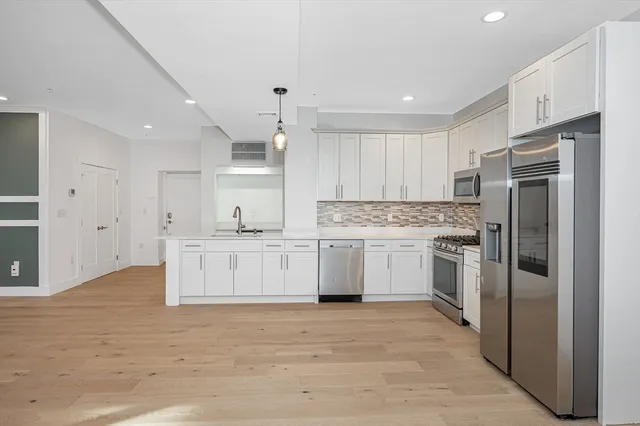 a kitchen with white cabinets and stainless steel appliances
