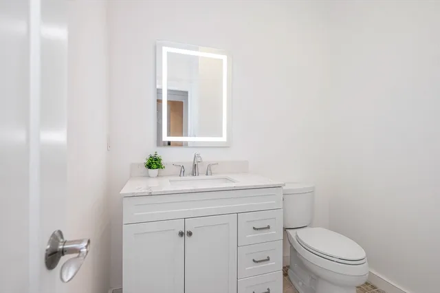 a bathroom with a toilet a sink a vanity and mirror