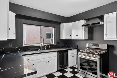 a kitchen with a checkered floor and a black refrigerator