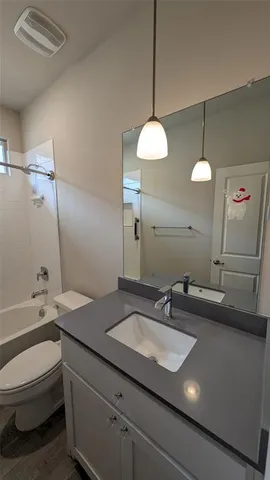 a bathroom with a granite countertop bathtub shower sink vanity and toilet
