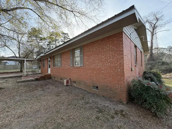a backyard of a house with wooden fence and large trees