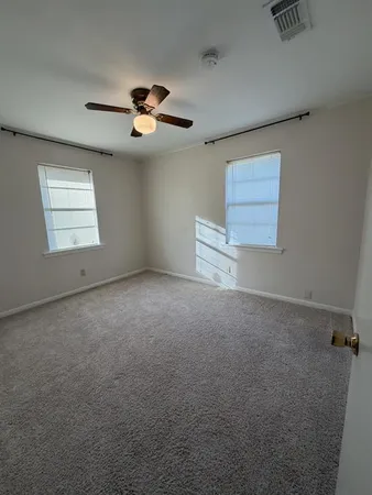 an empty room with windows and ceiling fan