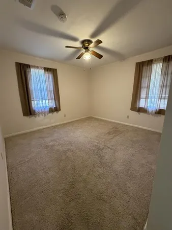 an empty room with windows and fan