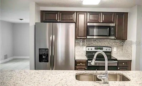 a kitchen with granite countertop a refrigerator and a sink