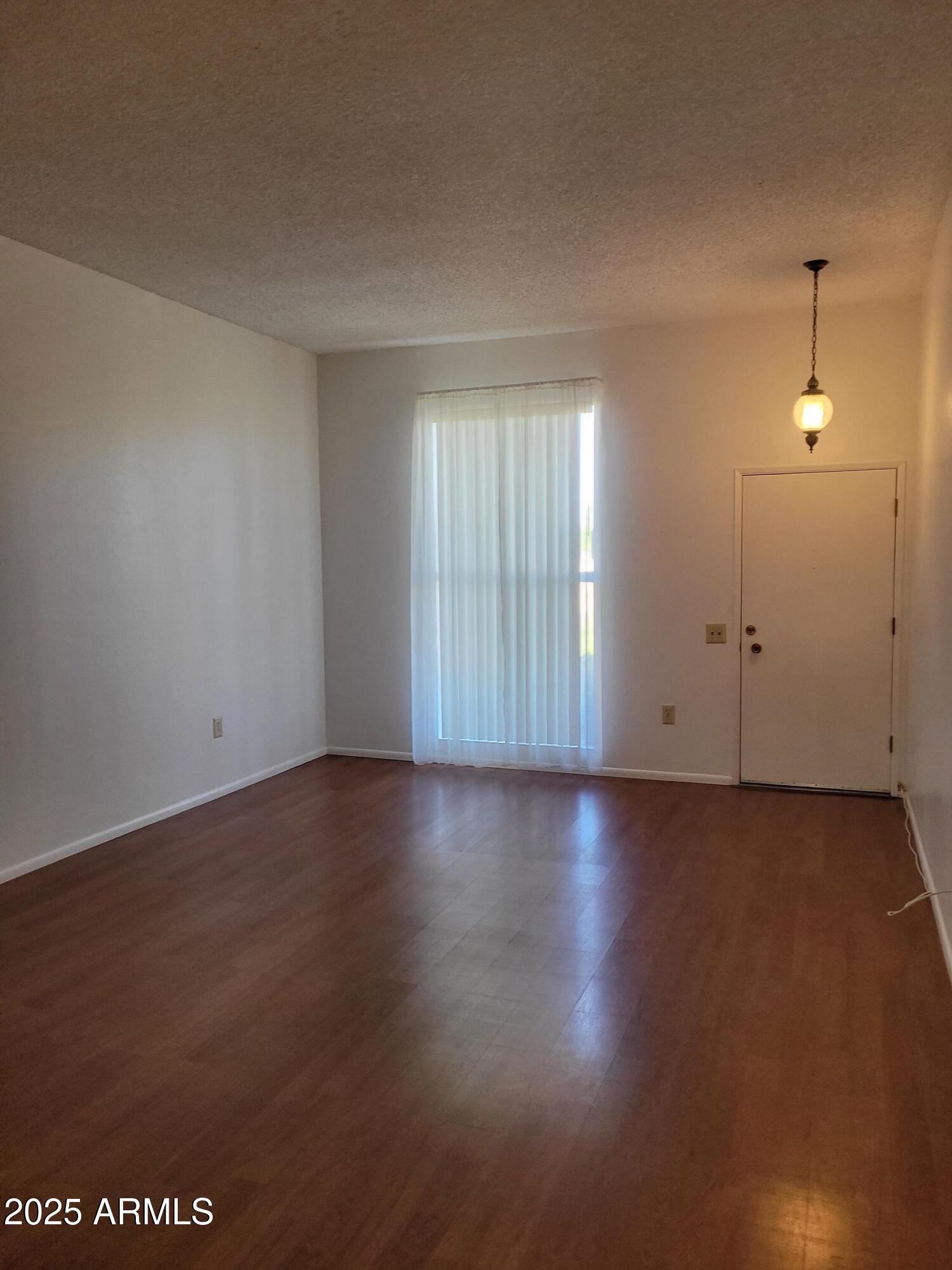 10060 West Royal Oak Road, Unit B Sun City, AZ 85351 - Photo 3 of 26 an empty room with wooden floor and windows
