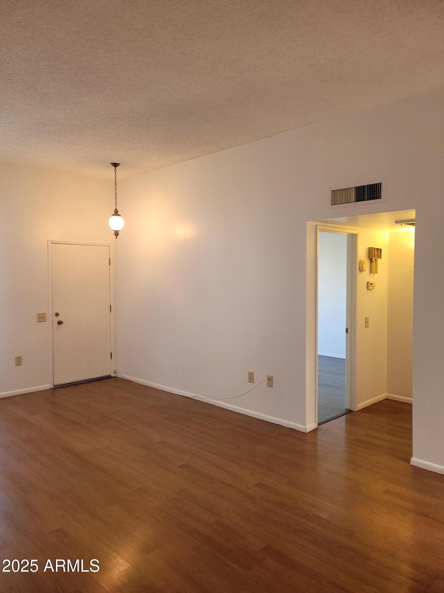 10060 West Royal Oak Road, Unit B Sun City, AZ 85351 - Photo 4 of 26 an empty room with wooden floor and windows