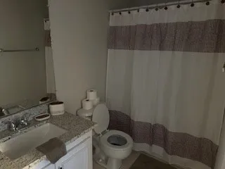 a bathroom with a granite countertop sink a toilet and a mirror