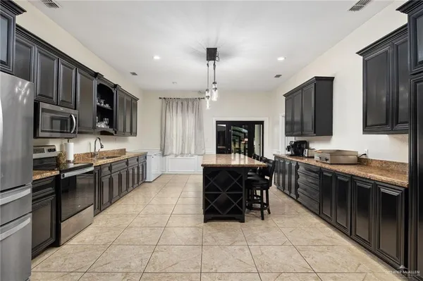 a kitchen with stainless steel appliances granite countertop a stove top oven a sink dishwasher a dining table and chairs