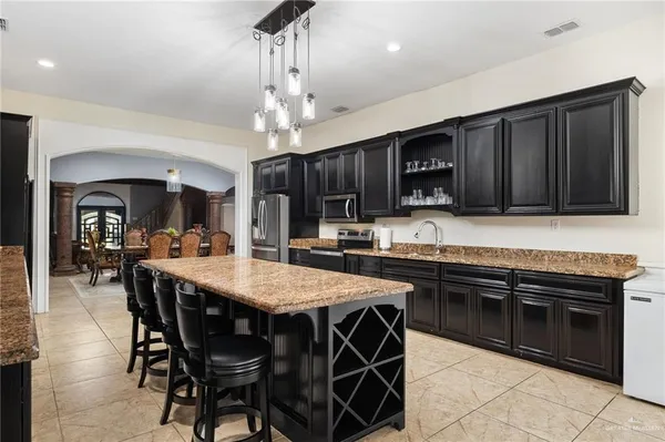 a kitchen with stainless steel appliances granite countertop wooden cabinets a refrigerator a stove a sink and dishwasher