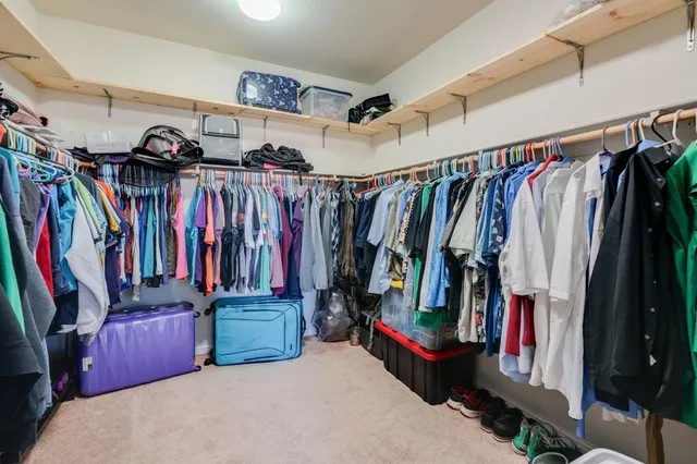 a view of walk in closet with clothes and shoes