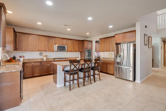 a kitchen with granite countertop a refrigerator and a stove top oven