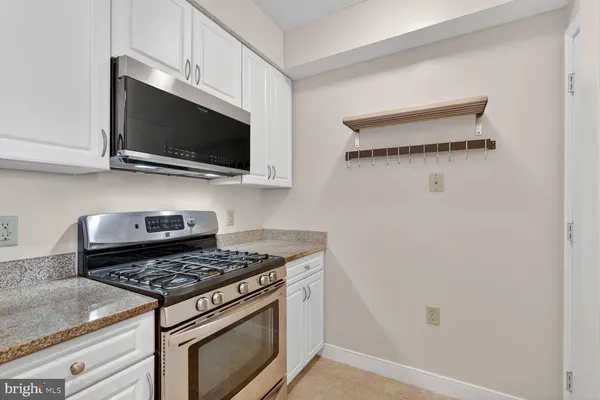 a kitchen with granite countertop a sink stainless steel appliances white cabinets and a granite counter tops