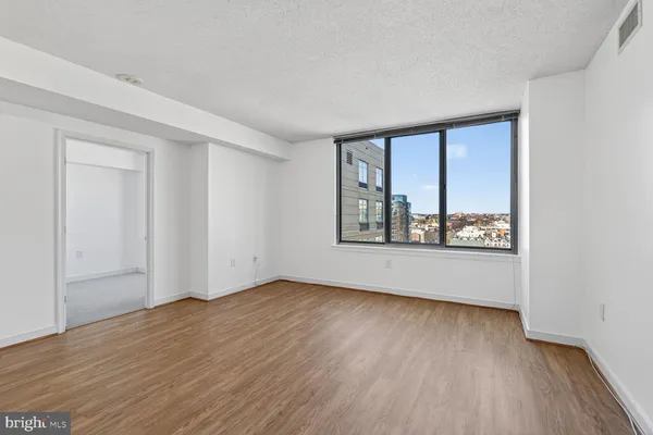 a view of an empty room with a window and wooden floor