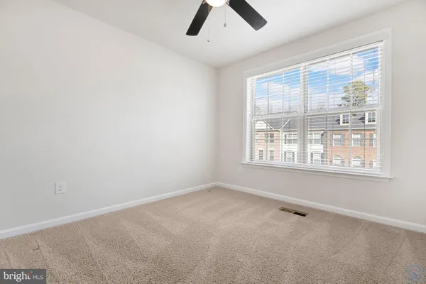 an empty room with chandelier fan and windows
