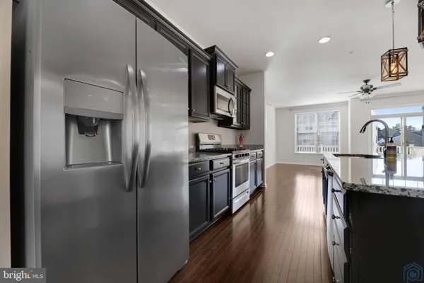 a kitchen with stainless steel appliances granite countertop a refrigerator a stove and a sink with wooden floor