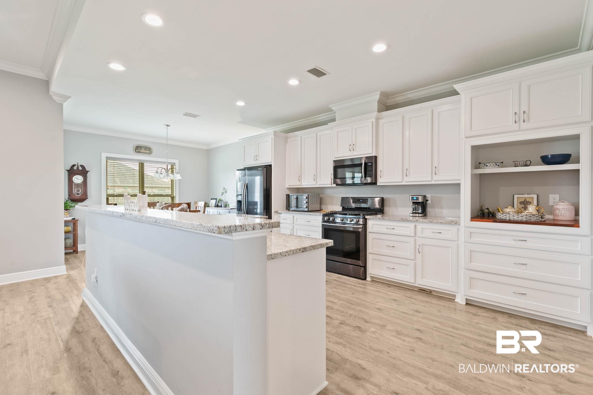 9388 Pembrook Loop Fairhope, AL 36532 - Photo 18 of 53 Kitchen featuring a center island with sink, stainless steel appliances, white cabinets, crown molding, and decorative light fixtures