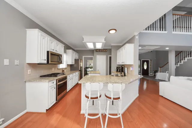 a large kitchen with cabinets wooden floor and stainless steel appliances